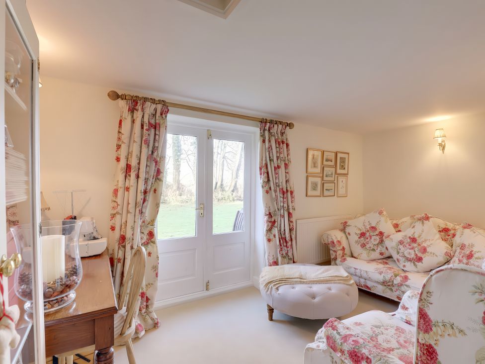 A living room with a door and floral sofa at Lake Cottage in Swindon