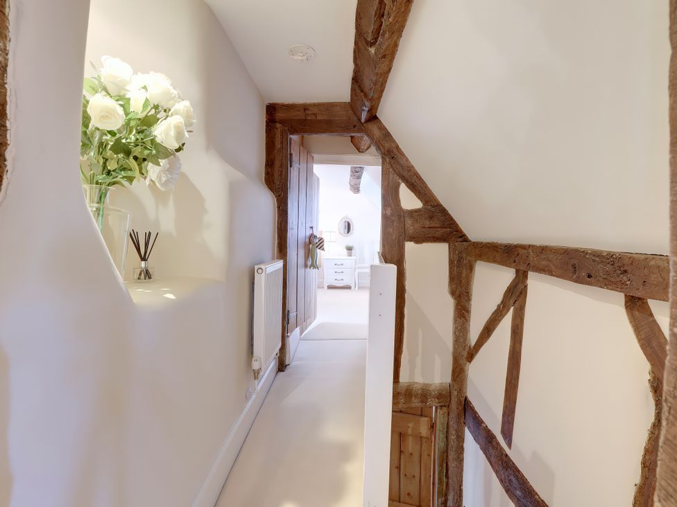 A hallway with a vase of flowers and a diffuser at Lake Cottage in Swindon
