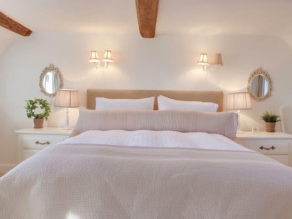 A bedroom with a bed and bedside tables at Lake Cottage in Swindon