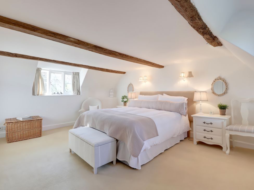 A bedroom with a bed, nightstand, and light fixtures at Lake Cottage in Swindon