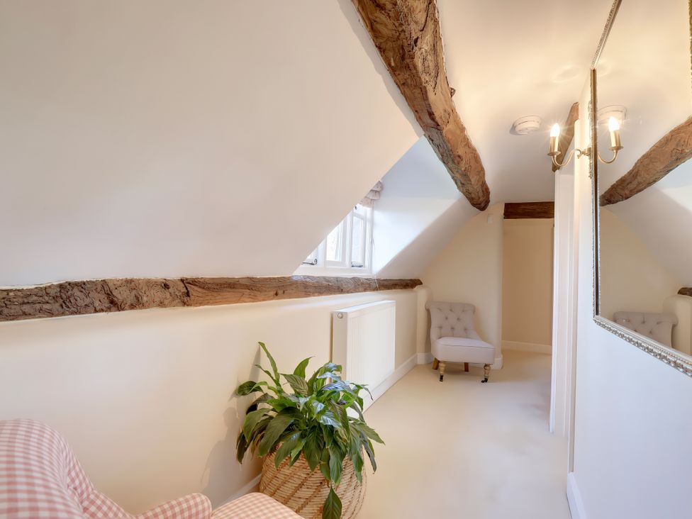 An attic space with a chair, a plant, and a mirror at Lake Cottage in Swindon
