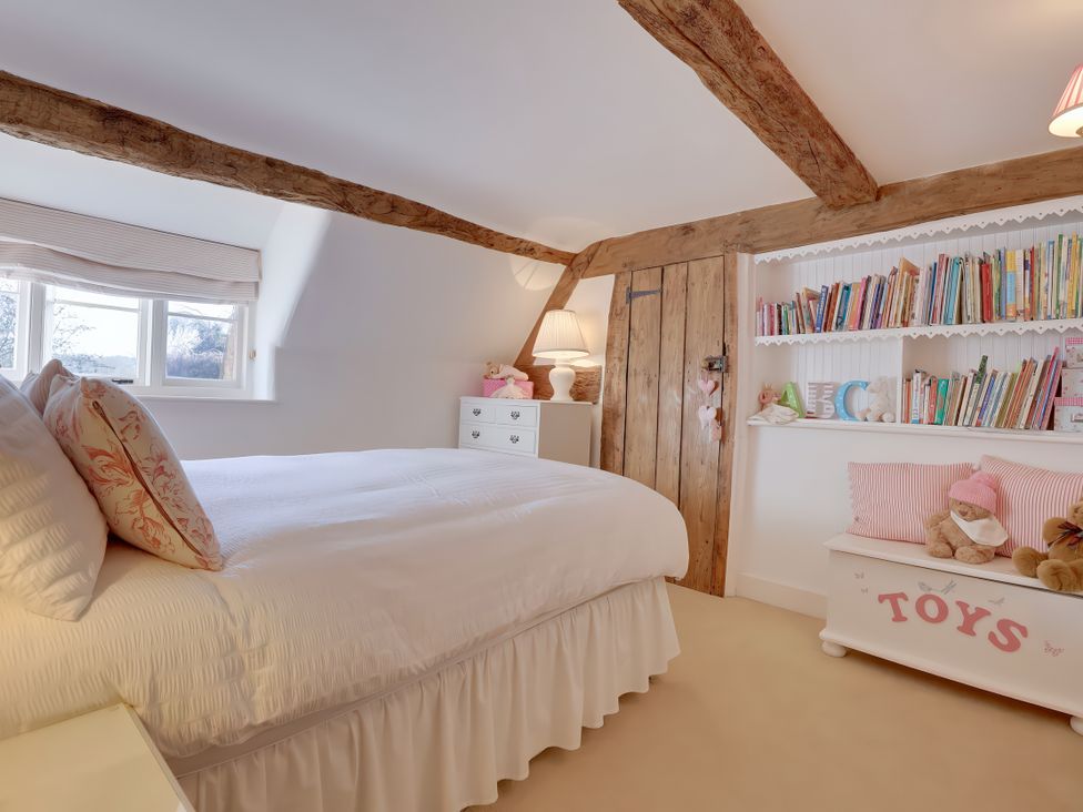 A bedroom with a bed and bookshelves at Lake Cottage in Swindon