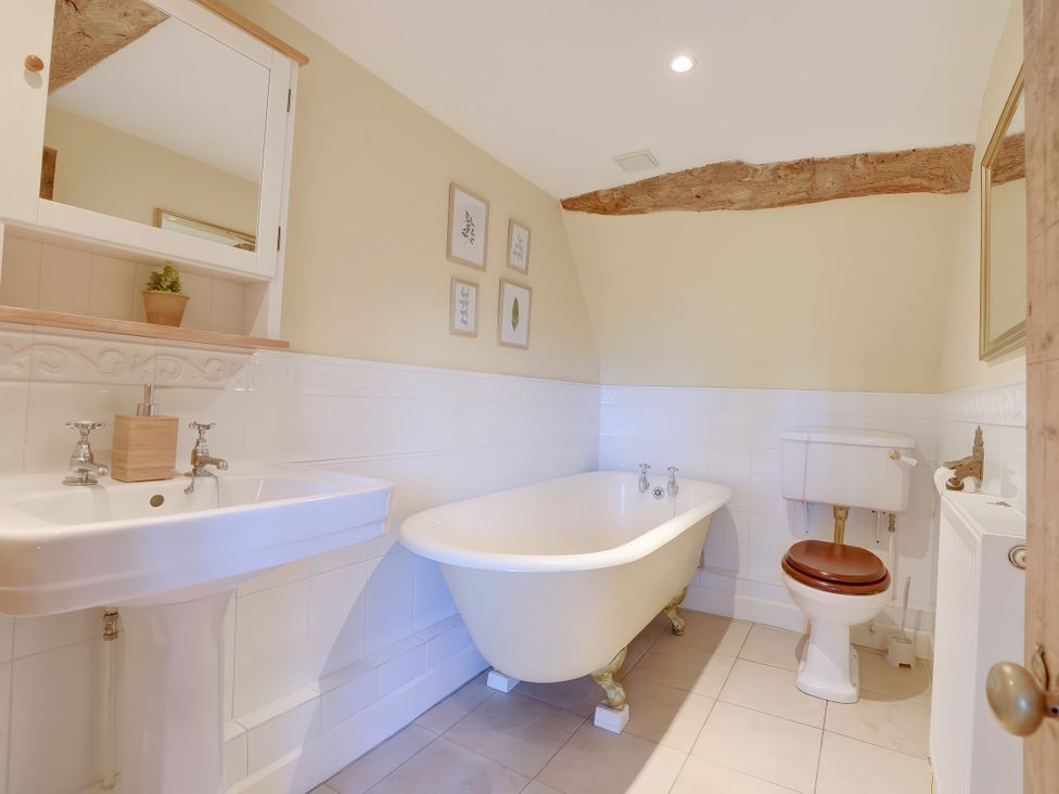 A bathroom with a sink, bath tub, and toilet at Lake Cottage in Swindon