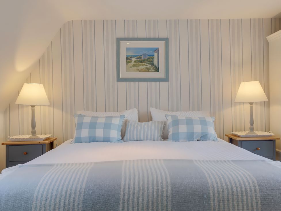 A bedroom with a bed and bedside lamps at Lake Cottage in Swindon