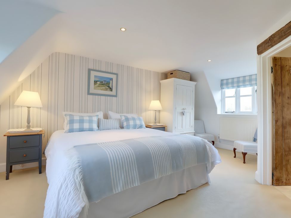 A bedroom with a large bed and a nightstand at Lake Cottage in Swindon