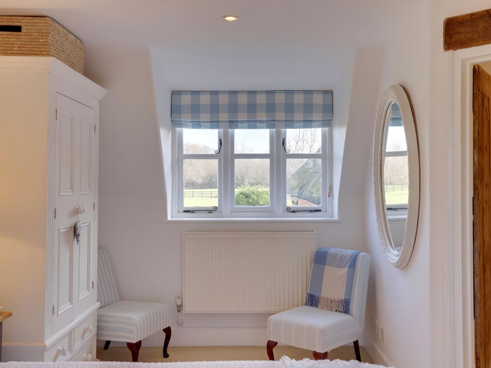 A bedroom with a wardrobe and two chairs at Lake Cottage in Swindon