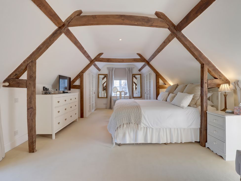 A bedroom with a bed and dresser at Lake Cottage in Swindon