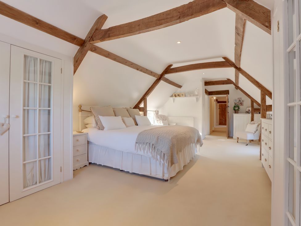 A bedroom with a bed and wardrobe at Lake Cottage in Swindon