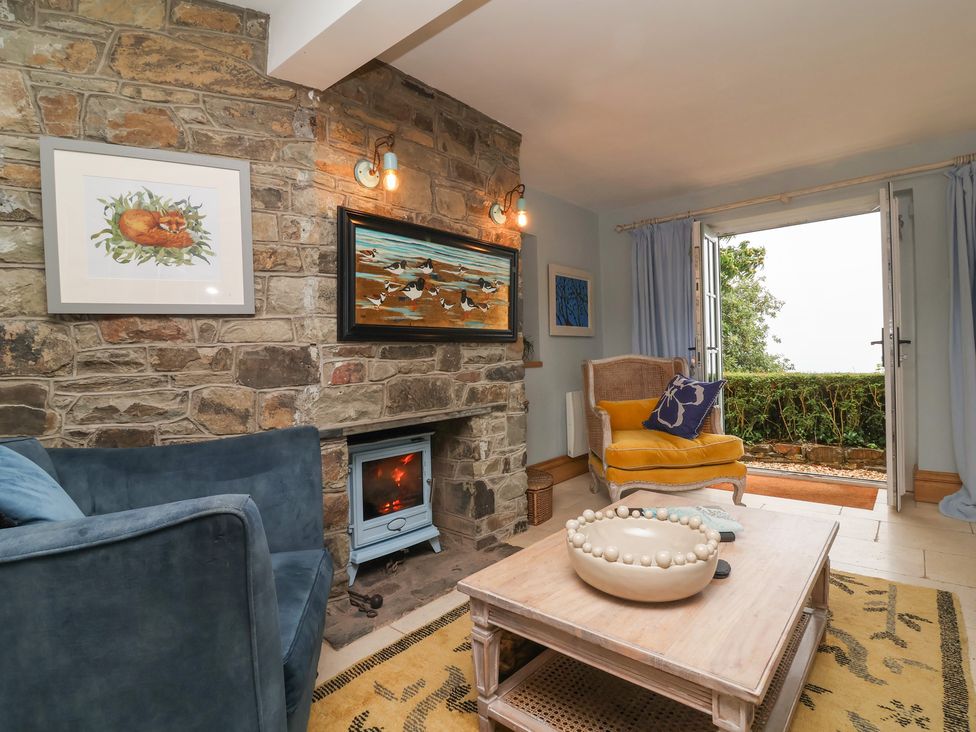 A living room with a fireplace and artwork at Rookery Cottage in Lynton
