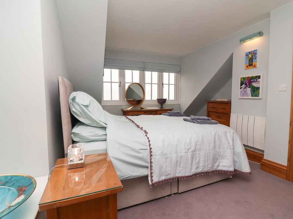 A bedroom with a bed, bedside table and mirror at Rookery Cottage in Lynton