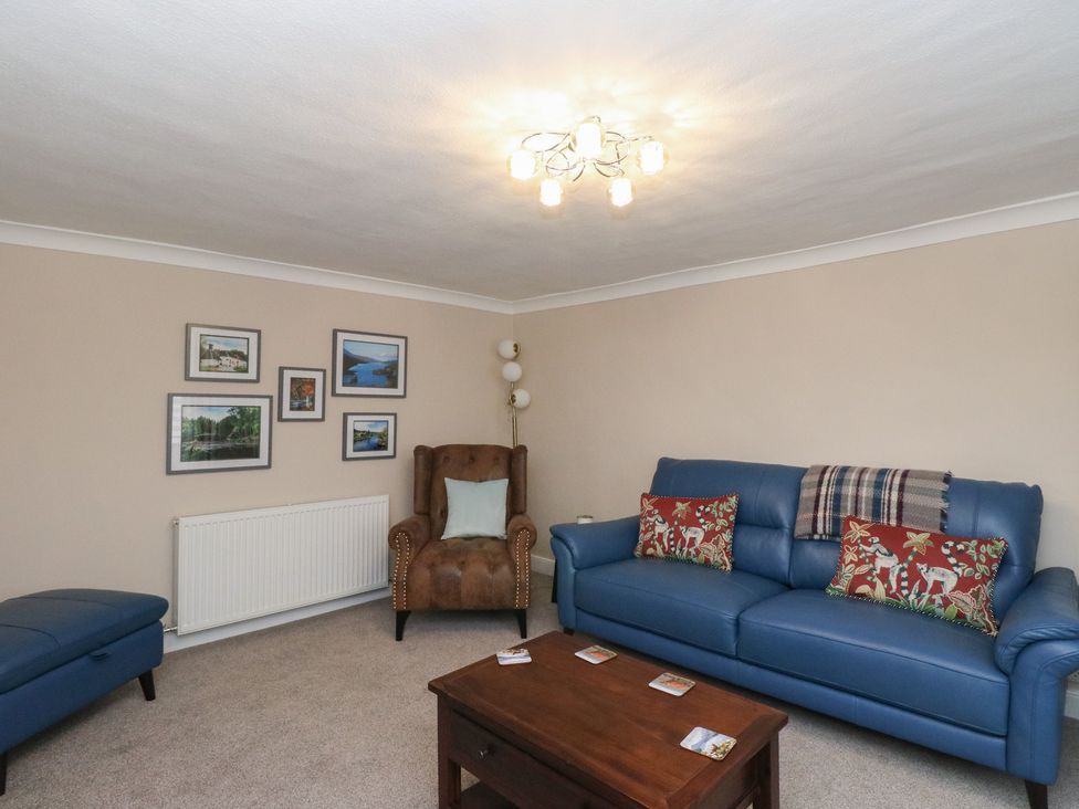 A living room with a blue sofa and a brown chair at Pirnie's in Pitlochry