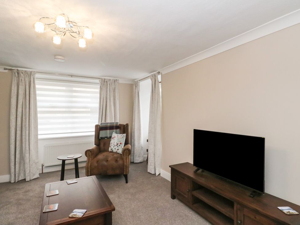 A living room with a sofa, chair, and television at Pirnie's in Pitlochry