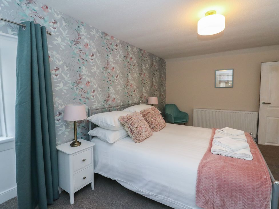 A bedroom with a bed and nightstand at Pirnie's in Pitlochry