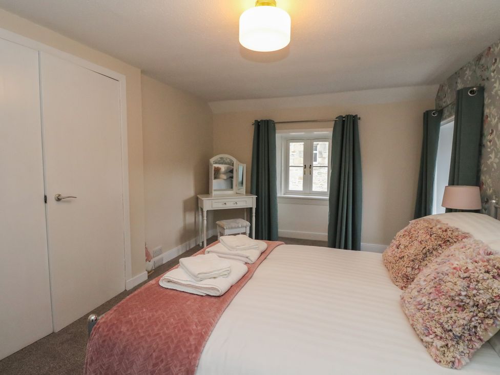 A bedroom with a bed, dresser and curtains at Pirnie's in Pitlochry