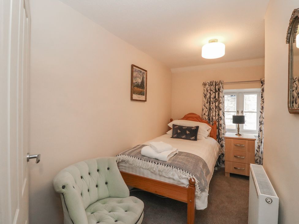 A bedroom with a single bed and an armchair at Pirnie's in Pitlochry