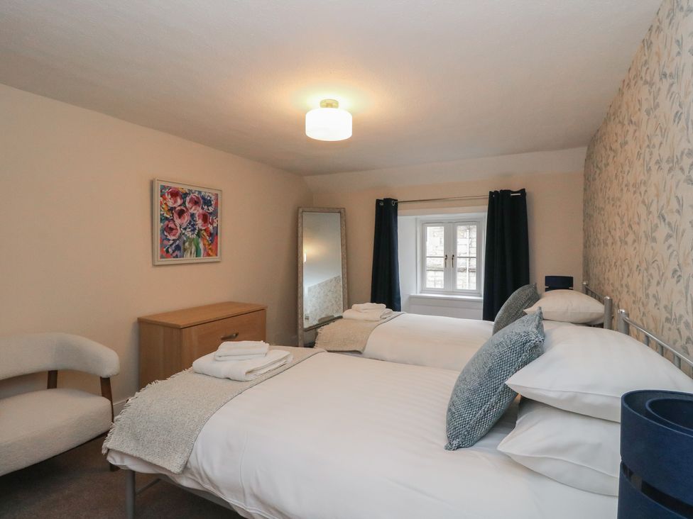 A bedroom with two beds, a mirror and a dresser at Pirnie's in Pitlochry