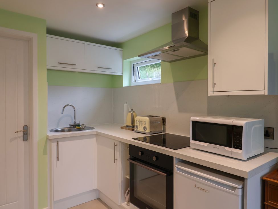 A kitchen with a sink, oven, microwave, and countertops at Cherry Pip in Charmouth