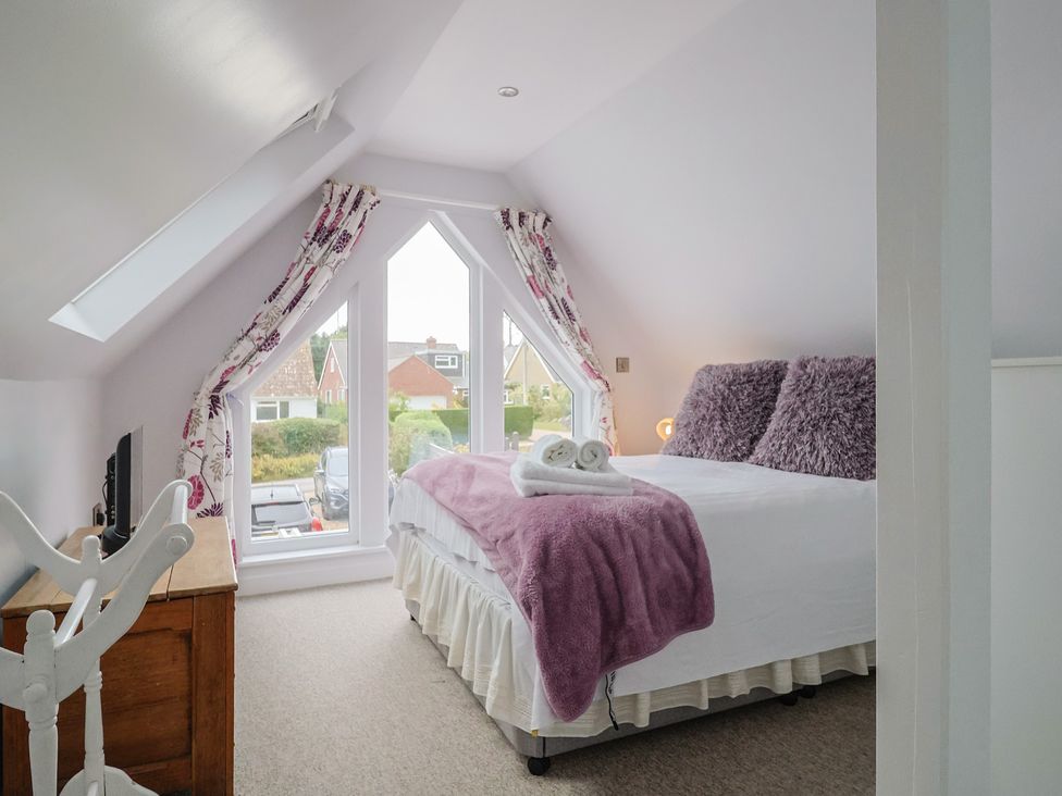 A bedroom with a bed and windows at Cherry Pip in Charmouth
