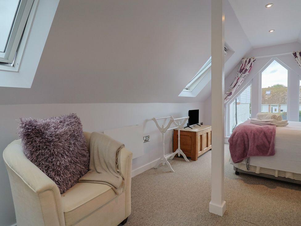 A bedroom with a bed and a chair at Cherry Pip in Charmouth