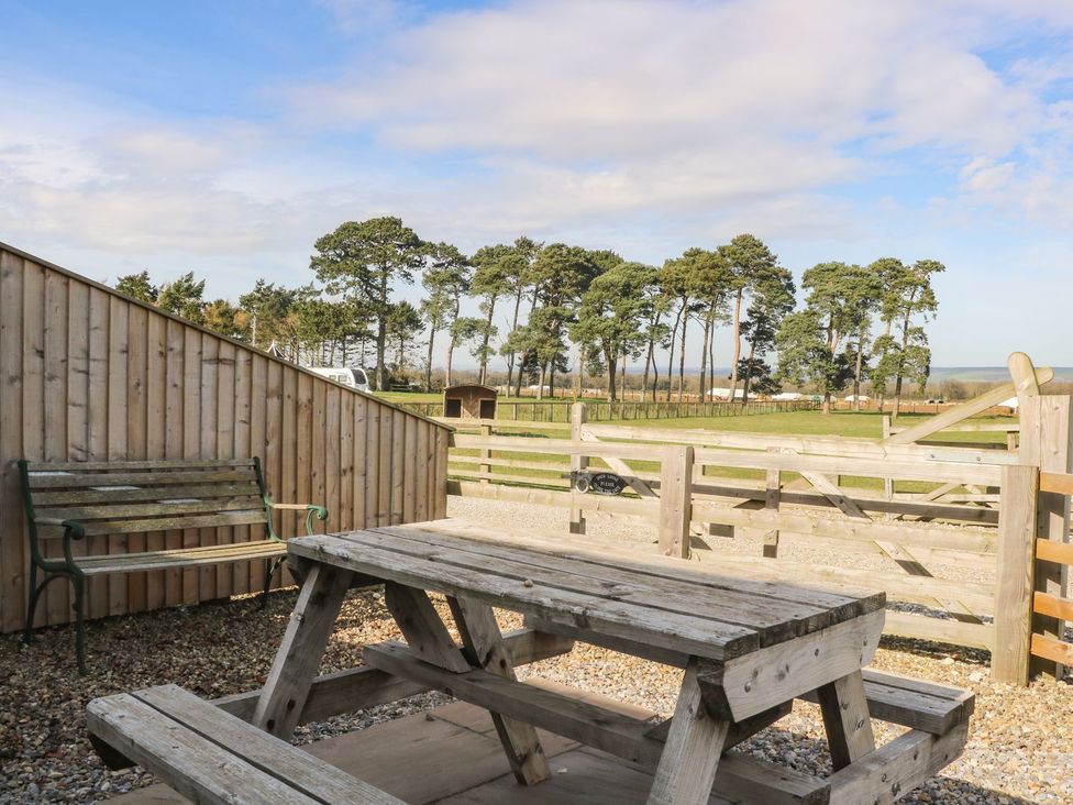 An outdoor area with a table and bench overlooking a field at 1 Small in Malton