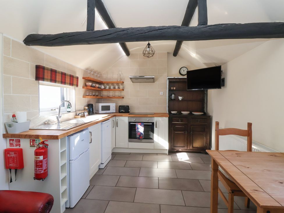 A kitchen with appliances and dining table at Cowshed Cottage East Knapton near Rillington