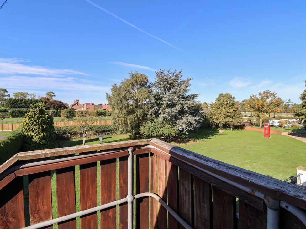 A balcony view overlooking trees and grass at East Cottage in East Knapton near Rillington
