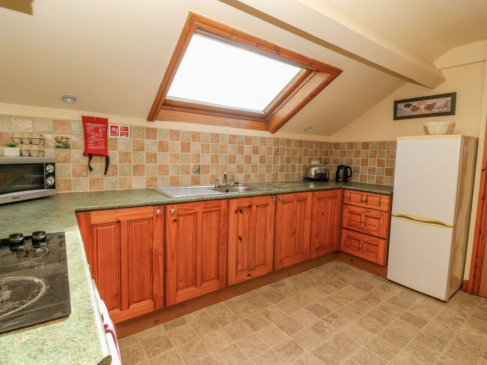 A kitchen with wooden cabinets and essential appliances at 3 Marinas side in Malton