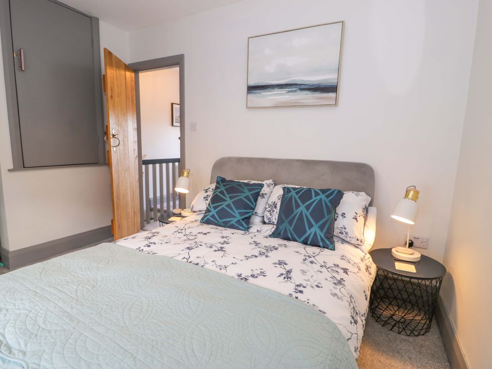 A bedroom with a bed, bedside table and lamps at 8 Watkin Street in Conwy