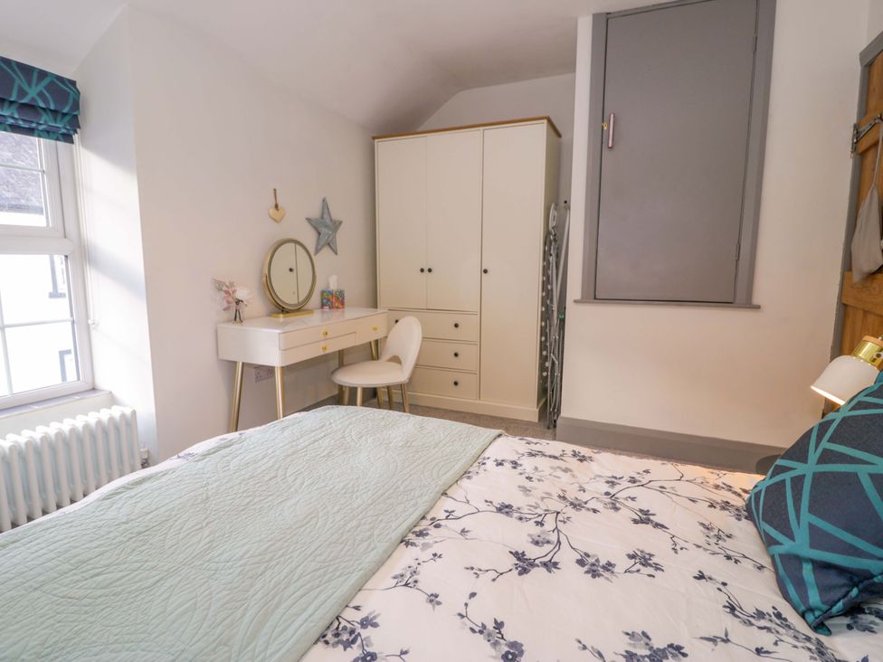 A bedroom with a bed, dresser, mirror, and wardrobe at 8 Watkin Street in Conwy