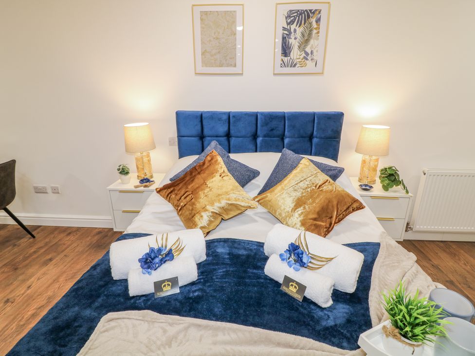 A bedroom with a blue bed and decorative pillows at 2 in Peterborough