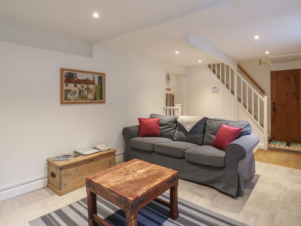 A living room with a sofa and wooden table at Cherry Cottage