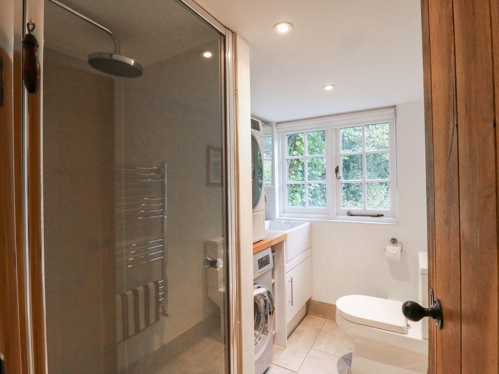 A bathroom with a shower, toilet, and laundry area at Cherry Cottage