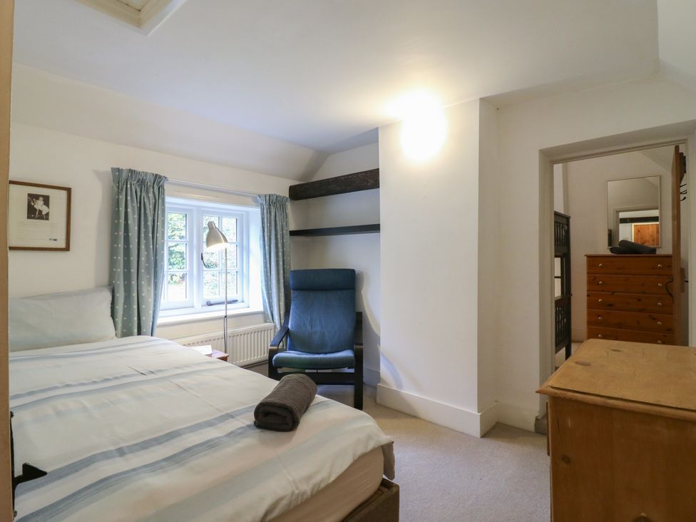 A bedroom with a bed and a chair at Cherry Cottage