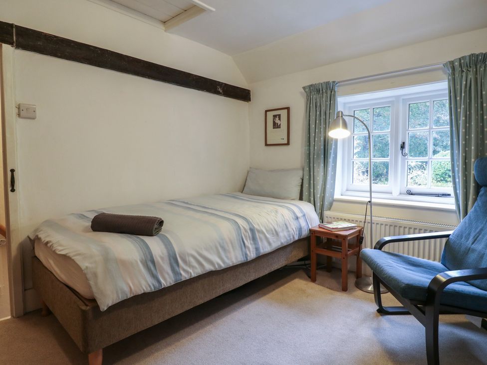 A bedroom with a bed and a chair at Cherry Cottage