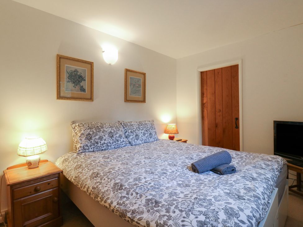 A bedroom with a bed and nightstand at Cherry Cottage