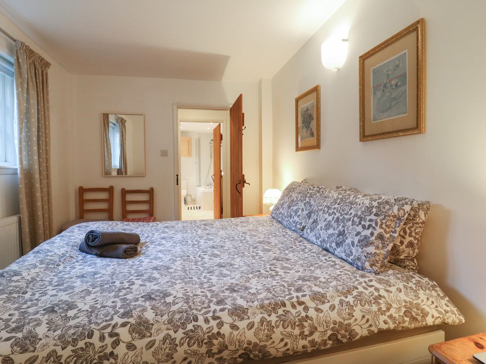 A bedroom with a bed and a door leading to a bathroom at Cherry Cottage