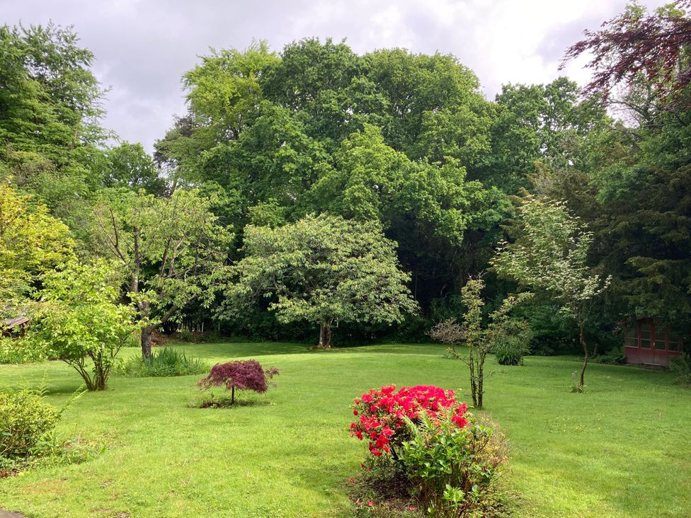 A garden with trees and a flower bed at Cherry Cottage in Crowborough