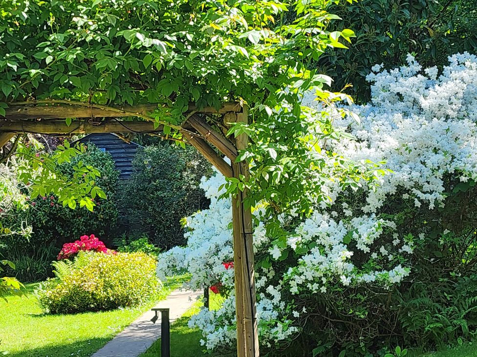 A garden with an archway and colorful flowers at Cherry Cottage in Crowborough