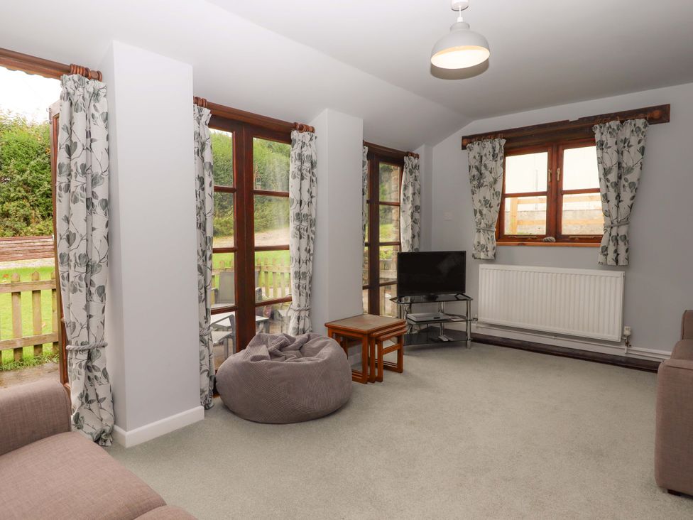 A living room with a sofa and a TV at The Milking Shippon at Thorne Langtree near Great Torrington