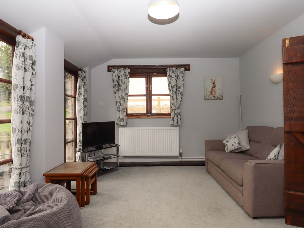 A living room with a sofa and TV at The Milking Shippon at Thorne, Langtree near Great Torrington