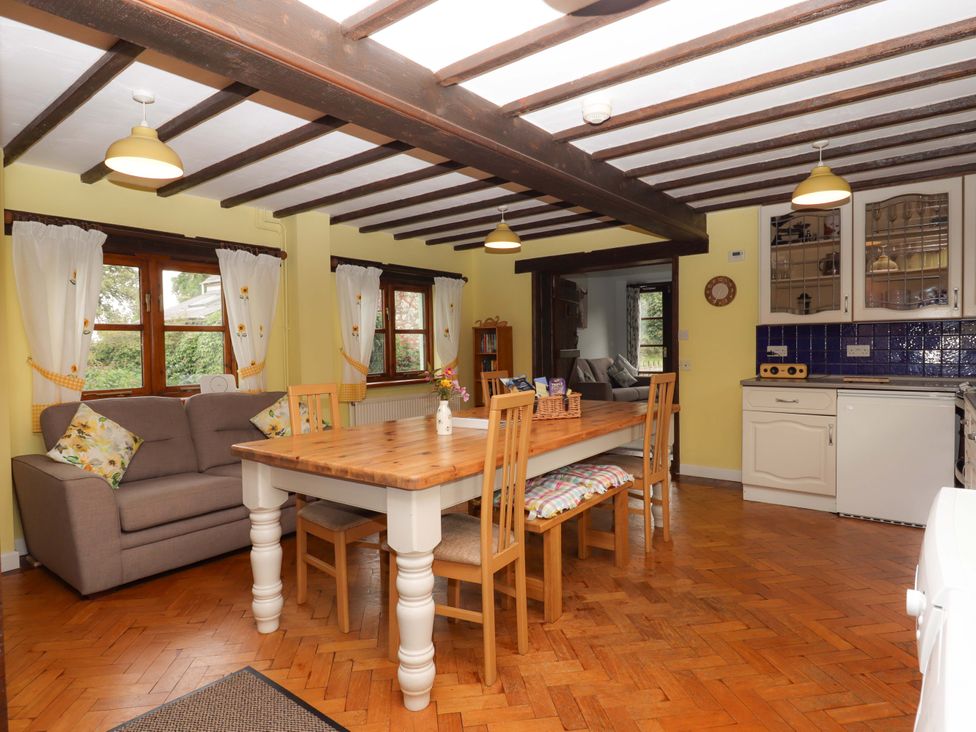 A dining room with a table and sofa at The Milking Shippon at Thorne, Langtree near Great Torrington