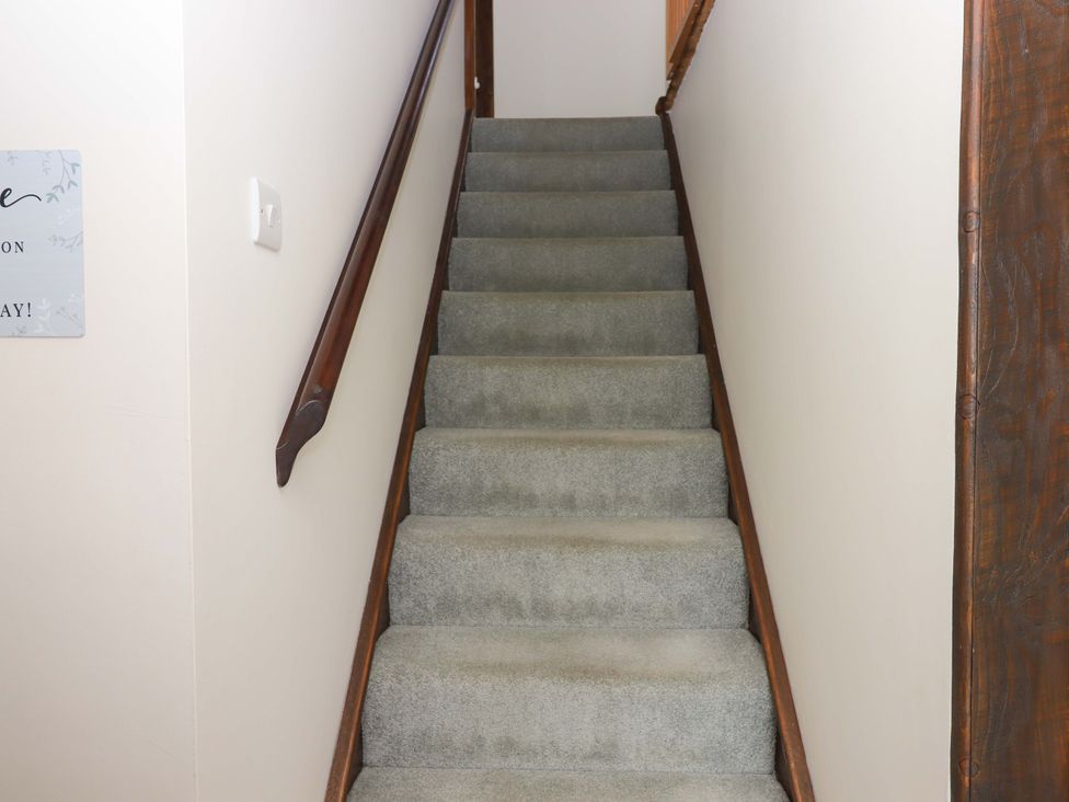 A staircase with carpet and handrail at The Milking Shippon at Thorne near Great Torrington