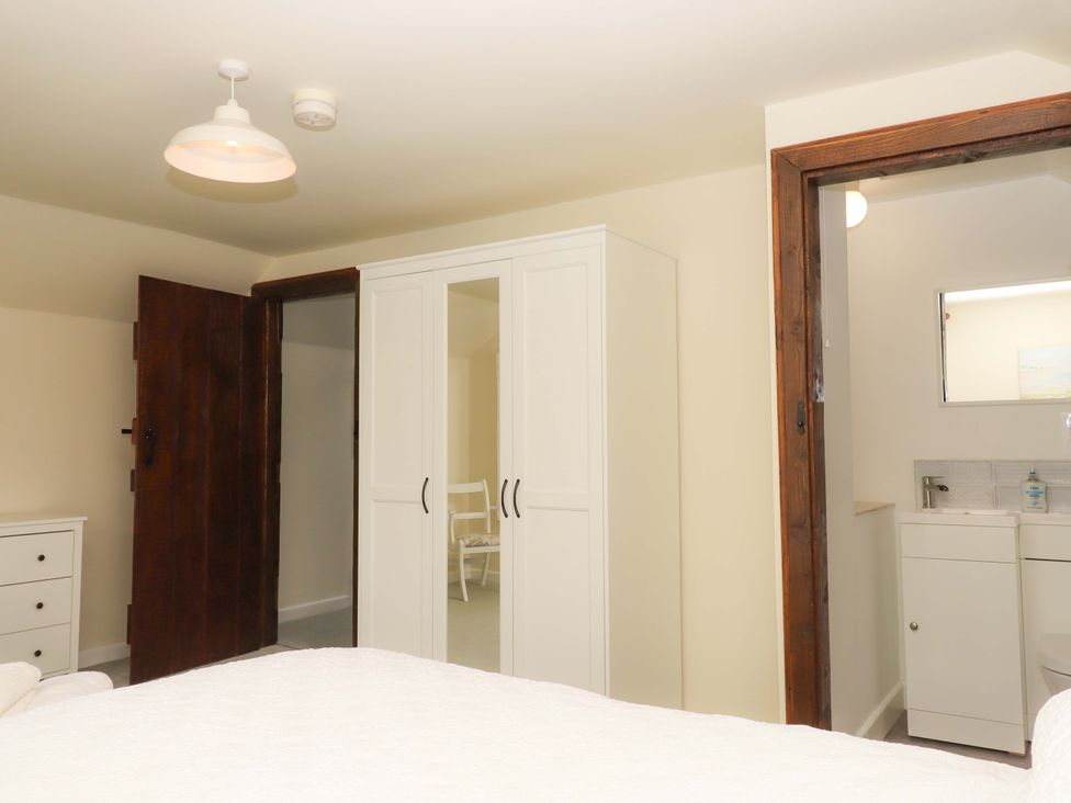 A bedroom with a wardrobe and sink at The Milking Shippon at Thorne near Great Torrington