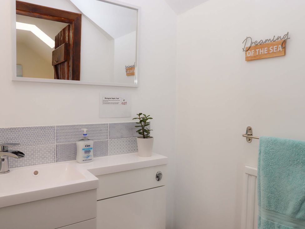 A bathroom with a mirror and sink at The Milking Shippon at Thorne, Langtree near Great Torrington