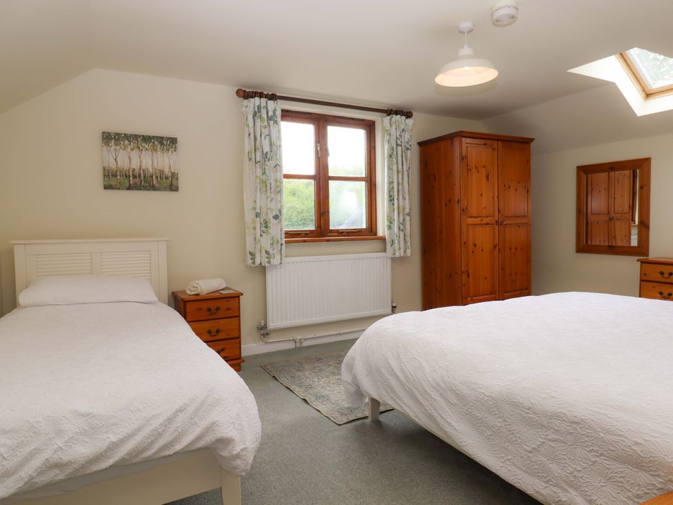 A bedroom with two beds and a wardrobe at The Milking Shippon at Thorne near Great Torrington