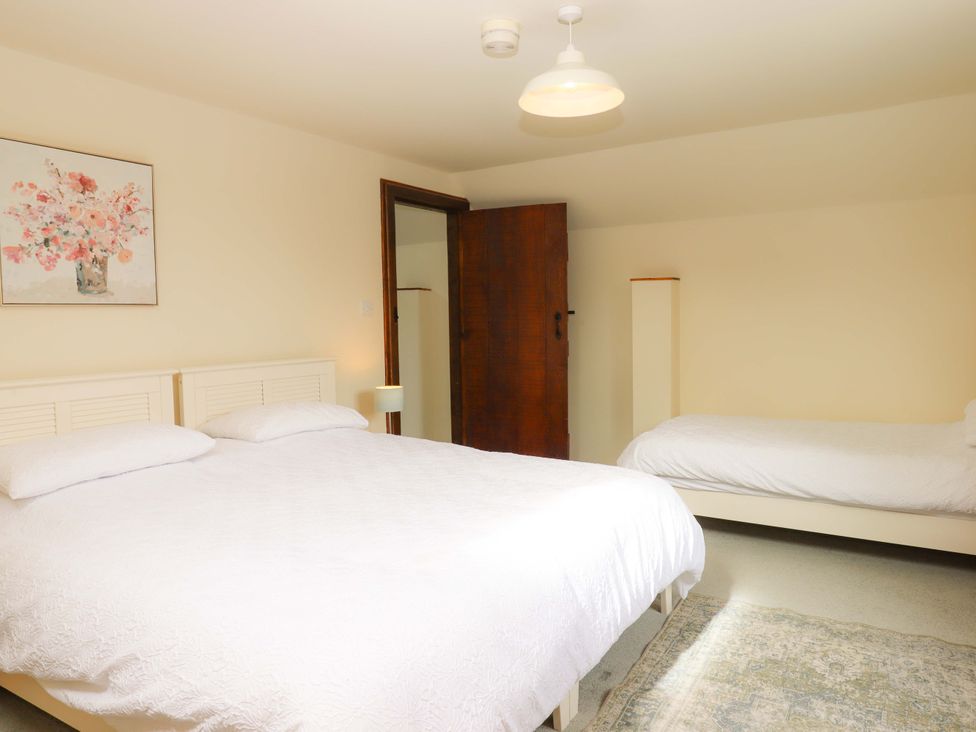 A bedroom with two beds and a picture on the wall at The Milking Shippon at Thorne Langtree near Great Torrington