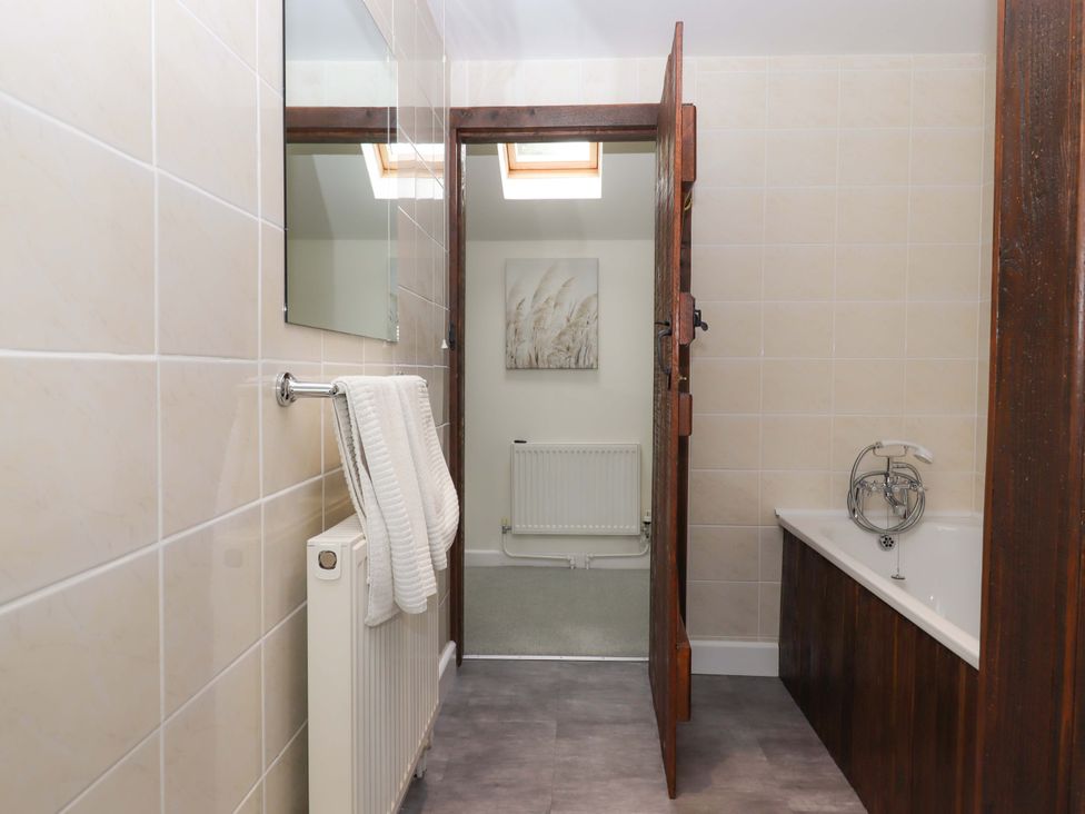 A bathroom with a bathtub and a towel rack at The Milking Shippon at Thorne Langtree near Great Torrington