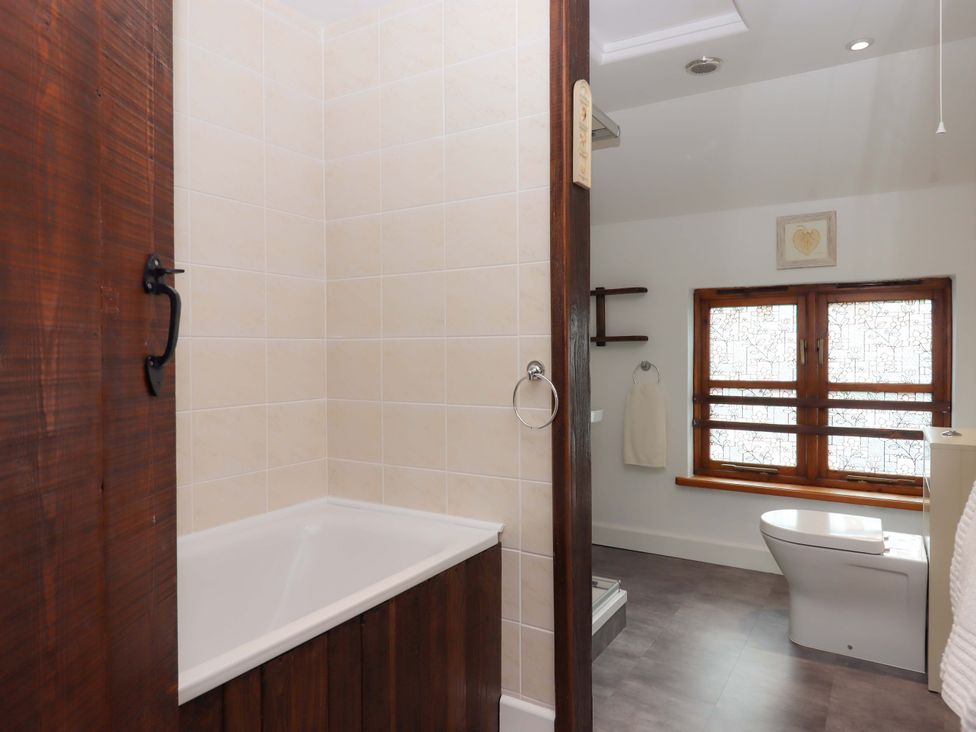 A bathroom with a bathtub and toilet at The Milking Shippon at Thorne near Great Torrington