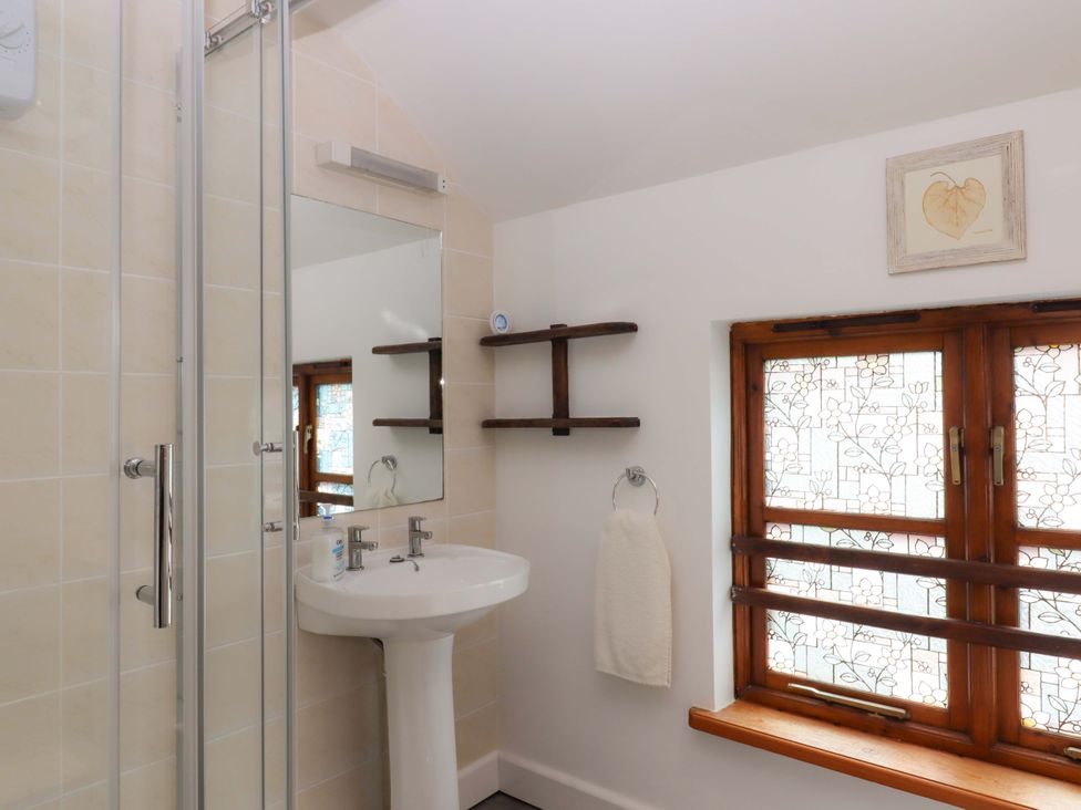 A bathroom with shower, sink, and window at The Milking Shippon at Thorne in Langtree near Great Torrington
