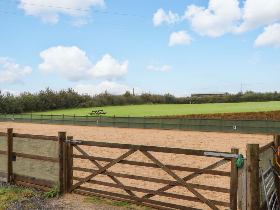 An outdoor horse arena with a picnic table at The Milking Shippon at Thorne Langtree near Great Torrington